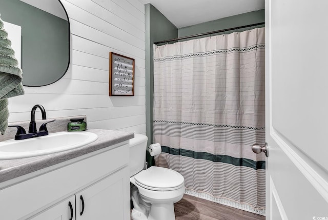 bathroom with wood-type flooring, vanity, wooden walls, and toilet