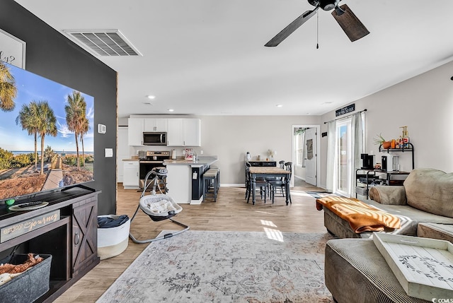 living room with ceiling fan, a healthy amount of sunlight, and light hardwood / wood-style floors