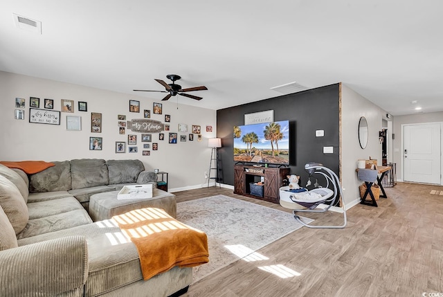 living room featuring ceiling fan, a fireplace, and light wood-type flooring