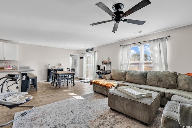 living room with ceiling fan and light hardwood / wood-style flooring