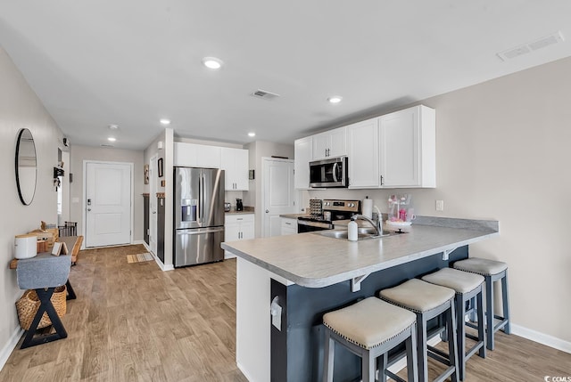 kitchen featuring white cabinetry, sink, light hardwood / wood-style floors, and appliances with stainless steel finishes