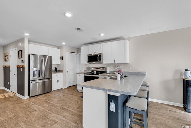 kitchen with white cabinetry, sink, a kitchen bar, kitchen peninsula, and stainless steel appliances