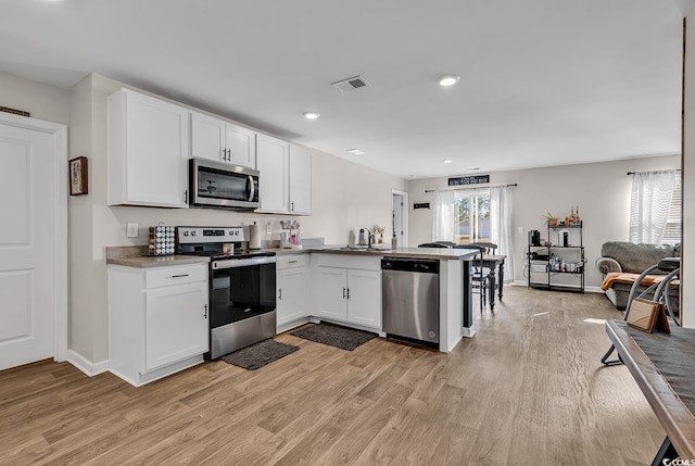 589 Talisman Trl, Longs, SC 29568 - kitchen with appliances with stainless steel finishes, a sink, light wood finished floors, a peninsula, and visible vents