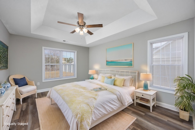 bedroom featuring dark wood-type flooring, a raised ceiling, and ceiling fan