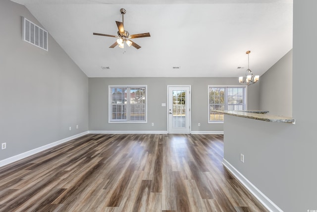 unfurnished living room with ceiling fan with notable chandelier, dark wood-type flooring, and vaulted ceiling