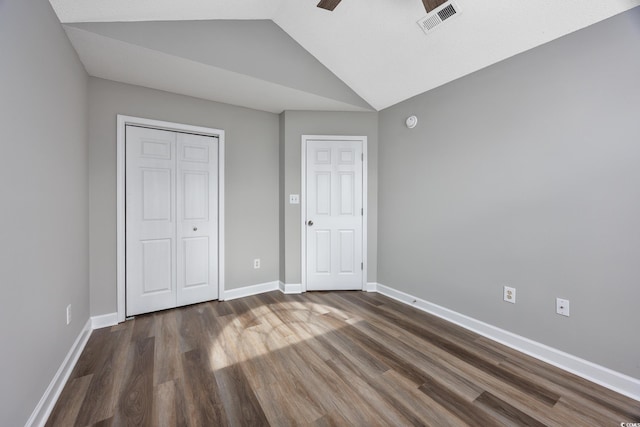 unfurnished bedroom featuring vaulted ceiling, dark wood-type flooring, and a closet