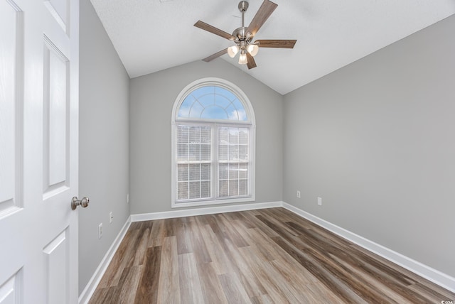 empty room with ceiling fan, wood-type flooring, and vaulted ceiling