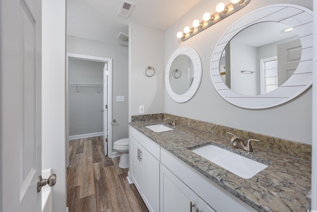 bathroom with hardwood / wood-style flooring, vanity, a textured ceiling, and toilet