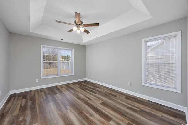 spare room with dark wood-type flooring, ceiling fan, a raised ceiling, and a textured ceiling