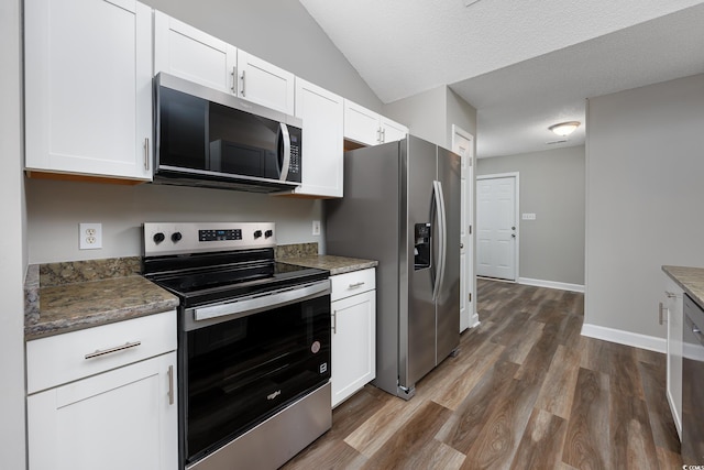 kitchen with white cabinetry, appliances with stainless steel finishes, dark hardwood / wood-style flooring, and dark stone counters