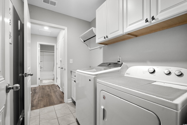 washroom with cabinets, light tile patterned flooring, and independent washer and dryer