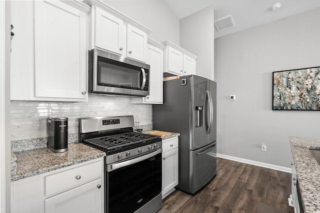 kitchen featuring white cabinets, dark hardwood / wood-style flooring, backsplash, stainless steel appliances, and light stone countertops