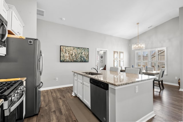 kitchen with white cabinetry, stainless steel appliances, light stone countertops, an island with sink, and decorative light fixtures