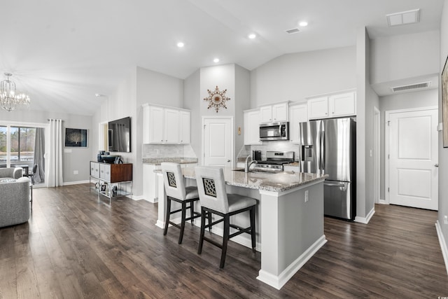 kitchen with a breakfast bar, white cabinetry, a kitchen island with sink, light stone counters, and stainless steel appliances