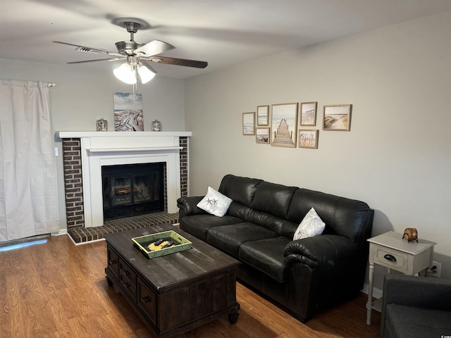 living room with hardwood / wood-style flooring, ceiling fan, and a fireplace