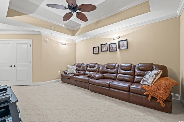 carpeted cinema room with a raised ceiling, ceiling fan, and ornamental molding