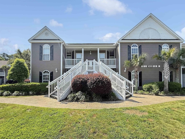 view of front facade featuring stairs, a front lawn, and a porch