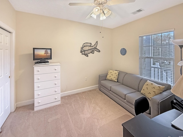 living area with baseboards, a ceiling fan, light colored carpet, and visible vents