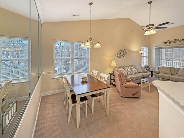 dining area with lofted ceiling, ceiling fan with notable chandelier, and light carpet