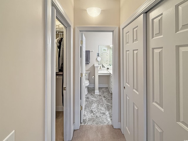 corridor with baseboards and light carpet