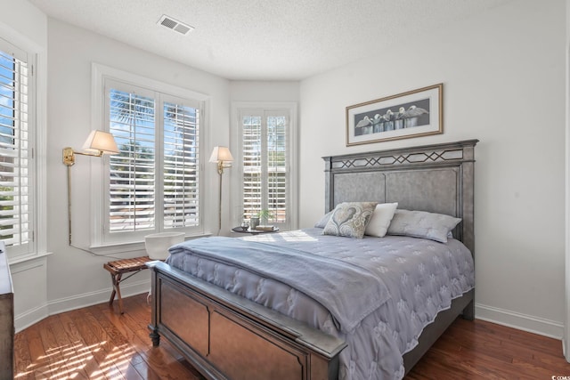 bedroom featuring multiple windows, dark wood-type flooring, and a textured ceiling