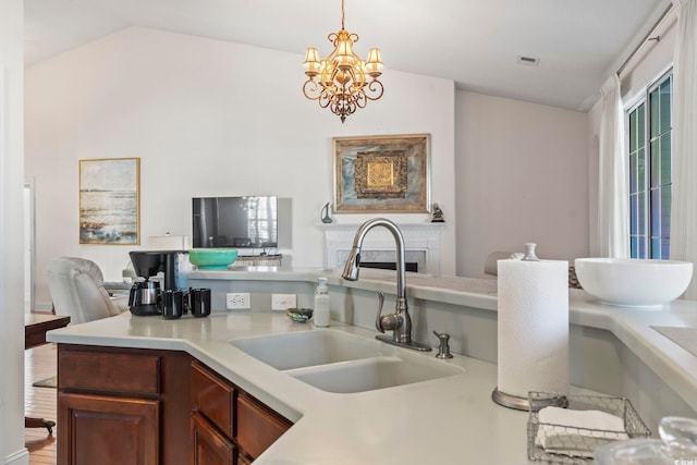 kitchen featuring pendant lighting, lofted ceiling, a chandelier, and sink