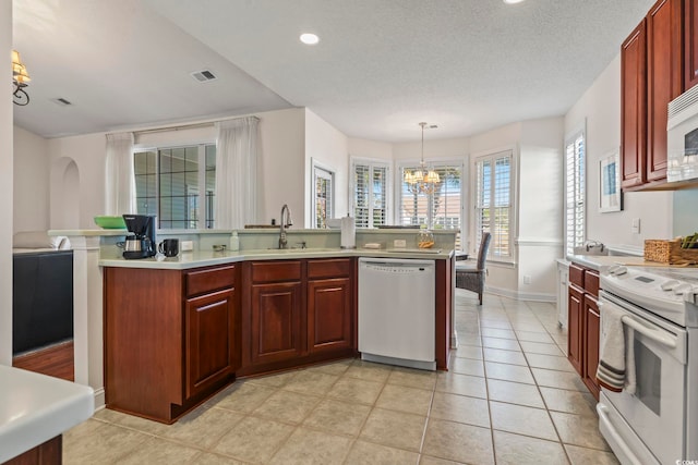 kitchen featuring light tile patterned flooring, decorative light fixtures, sink, white appliances, and an inviting chandelier