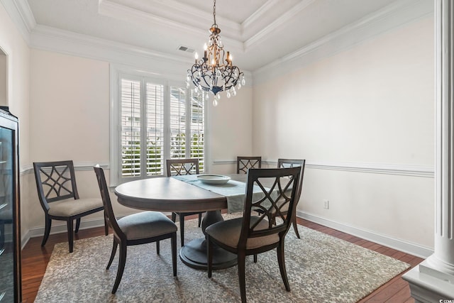 dining room featuring a raised ceiling, ornamental molding, and dark hardwood / wood-style flooring