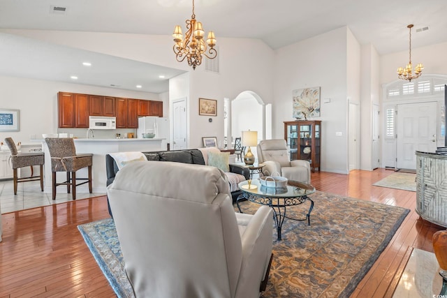 living room featuring high vaulted ceiling, light wood-type flooring, and a chandelier