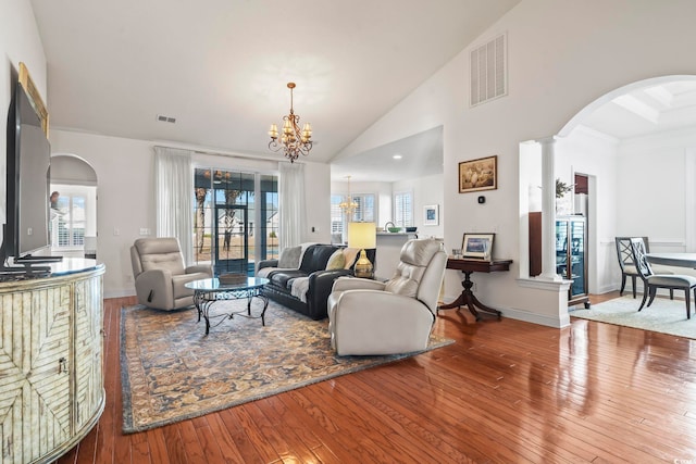 living room with ornate columns, plenty of natural light, wood-type flooring, and a notable chandelier