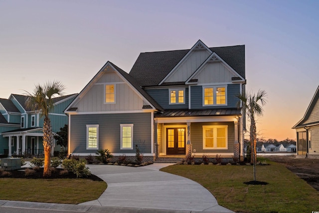 craftsman inspired home with concrete driveway, a standing seam roof, covered porch, a yard, and board and batten siding