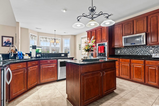 kitchen with appliances with stainless steel finishes, an inviting chandelier, a center island, light tile patterned flooring, and decorative light fixtures