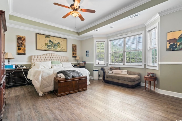 bedroom featuring a tray ceiling, crown molding, light hardwood / wood-style floors, and ceiling fan