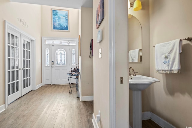 foyer entrance featuring french doors, sink, and light hardwood / wood-style flooring