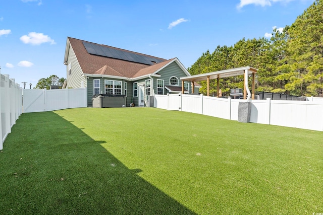 back of property featuring a lawn, a hot tub, and solar panels