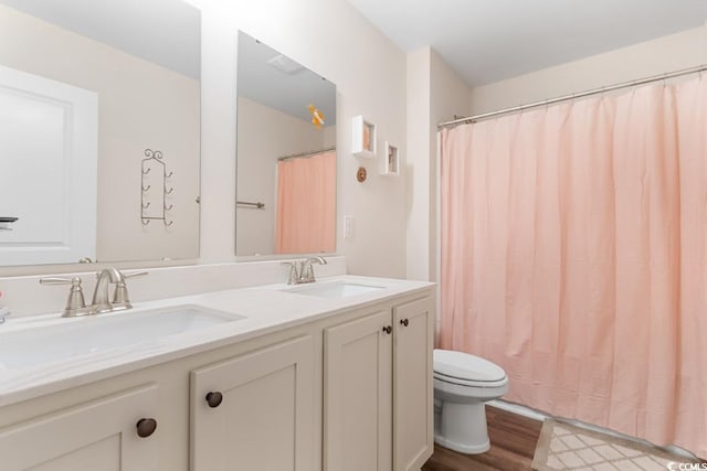 bathroom featuring wood-type flooring, walk in shower, vanity, and toilet