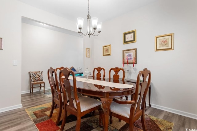 dining space with dark hardwood / wood-style flooring and an inviting chandelier