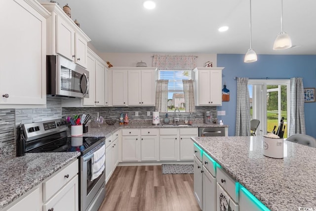 kitchen with pendant lighting, sink, white cabinets, backsplash, and stainless steel appliances