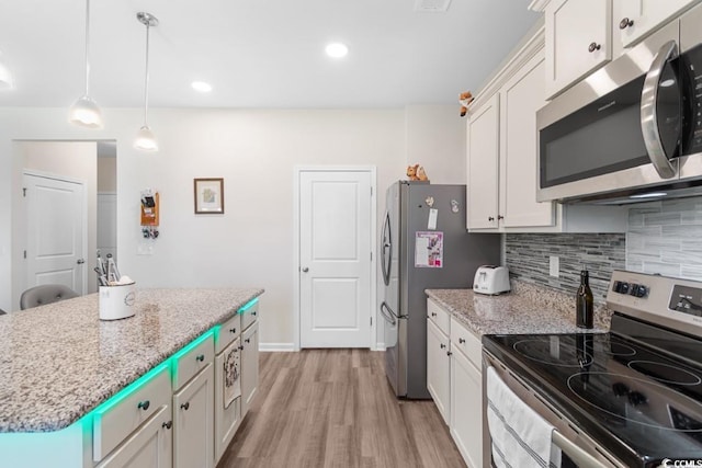 kitchen featuring a center island, light wood-type flooring, appliances with stainless steel finishes, white cabinets, and backsplash