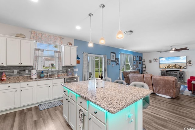 kitchen featuring a kitchen island, sink, white cabinets, a kitchen breakfast bar, and hanging light fixtures