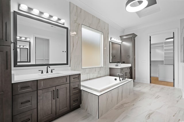 bathroom with vanity, crown molding, and tiled bath