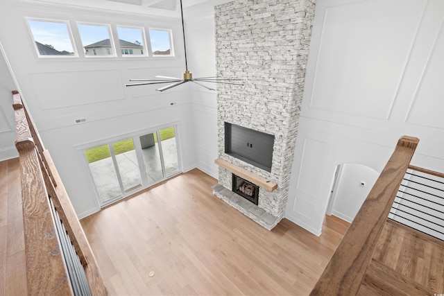 unfurnished living room featuring ceiling fan, a stone fireplace, and light hardwood / wood-style flooring