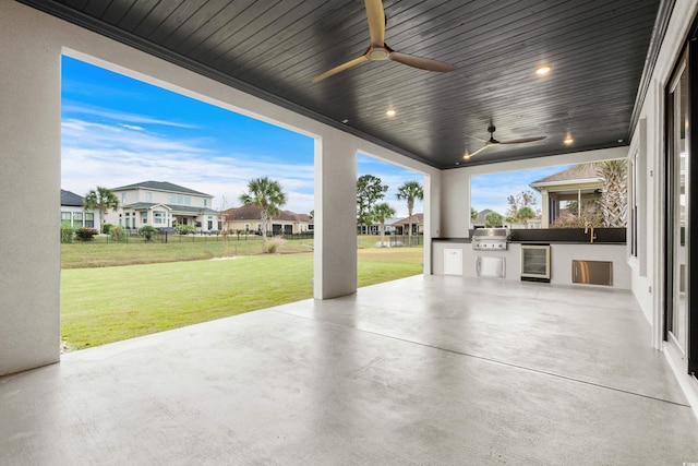 view of patio featuring exterior kitchen, area for grilling, wine cooler, and ceiling fan