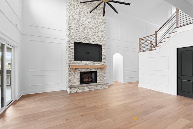 unfurnished living room featuring a fireplace, light hardwood / wood-style flooring, ceiling fan, and a high ceiling