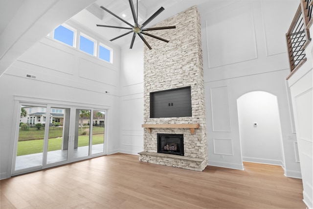 unfurnished living room featuring a stone fireplace, ceiling fan, and light hardwood / wood-style flooring