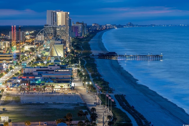 aerial view at dusk with a water view and a view of the beach