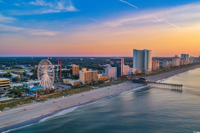 aerial view at dusk featuring a beach view and a water view