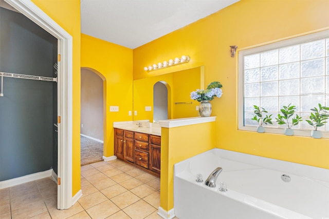 bathroom with a tub to relax in, vanity, and tile patterned flooring