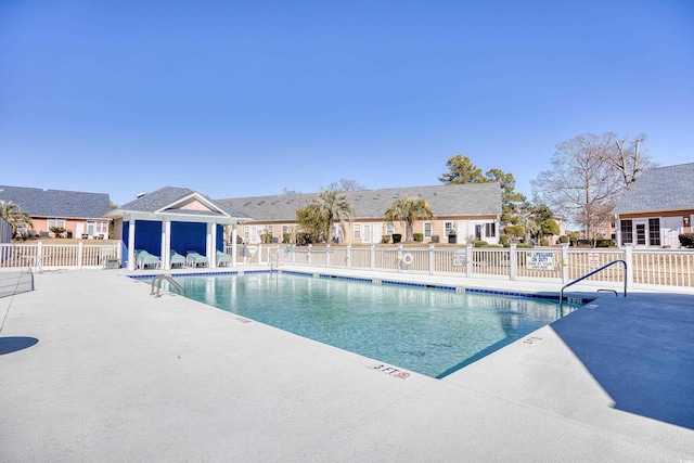 community pool featuring a residential view, fence, and a patio area