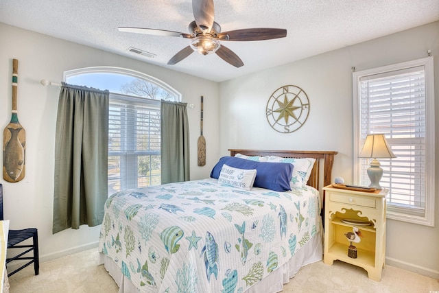 bedroom with visible vents, multiple windows, a textured ceiling, and ceiling fan